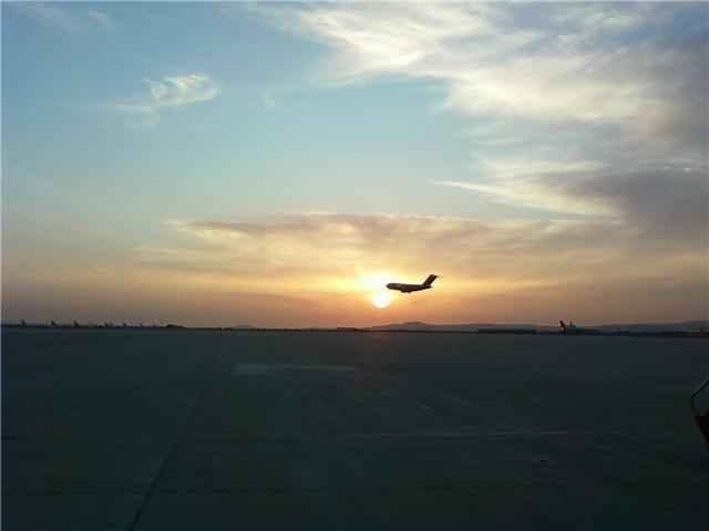A C-17 transport aircraft climbing out in silhouette against the setting sun